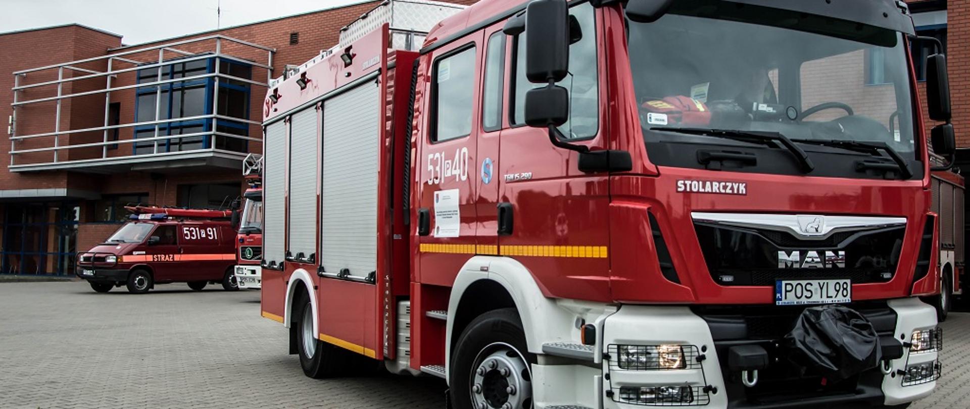 poglądowo samochód ratownictwa technicznego, w tle samochód ratownictwa wodnego oraz siedziba KP PSP