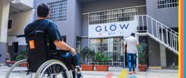 Mężczyzna na wózku inwalidzkim siedzi wejściem z napisem glow.