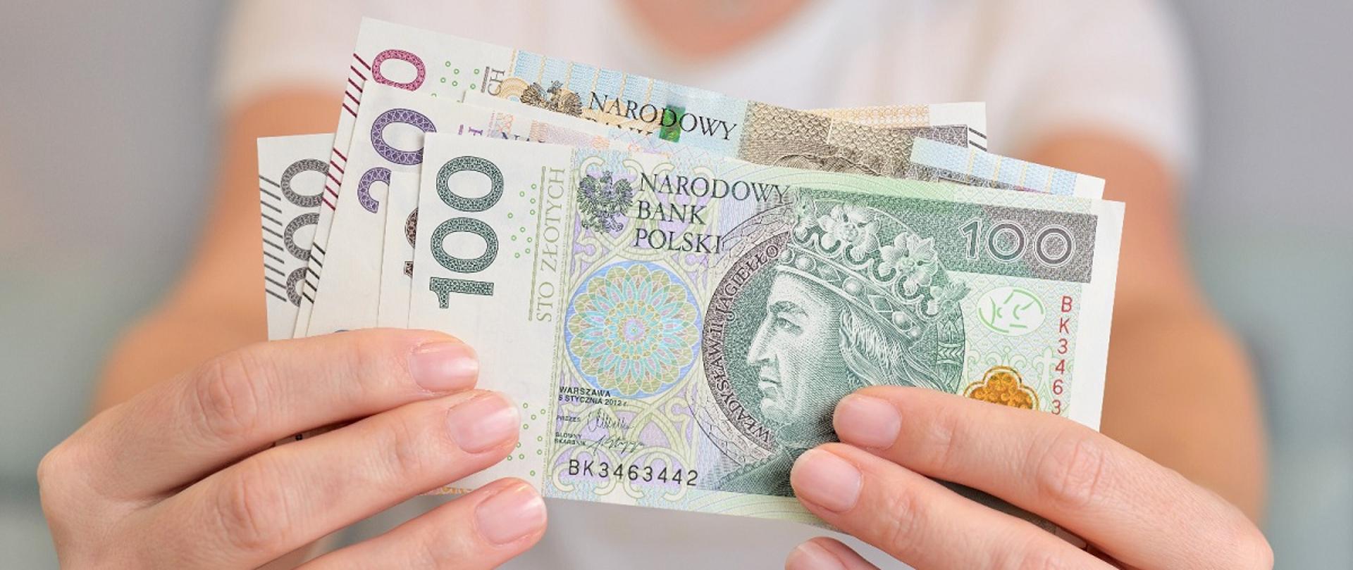 Dłonie kobiece trzymające polskie banknoty
