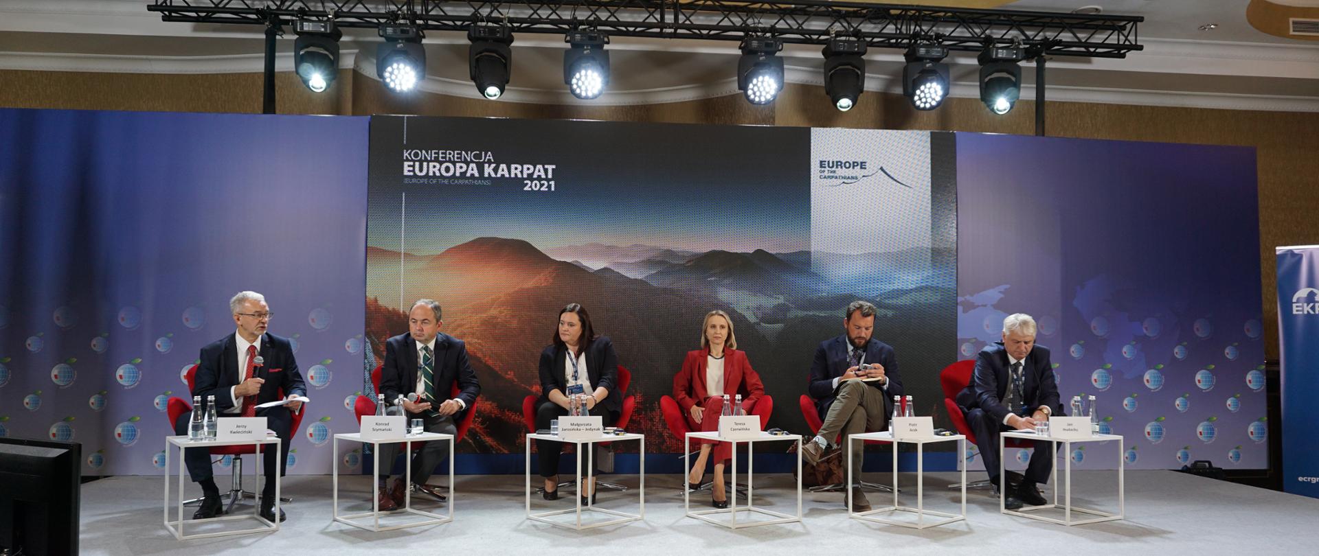 Zdjęcie przedstawia podest na którym siedzą wszyscy uczestnicy panelu dotyczącego nowej perspektywy dla Karpat.