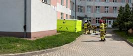 Na zdjęciu widoczne jest rozkładanie skokochronu przed budynkiem szpitala. Skokochron sprawiają strażacy z PSP oraz OSP ubraniu w umundurowanie specjalne.