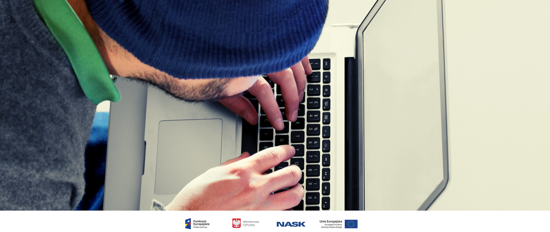 Mężczyzna w czapce patrzy na klawiaturę laptopa.