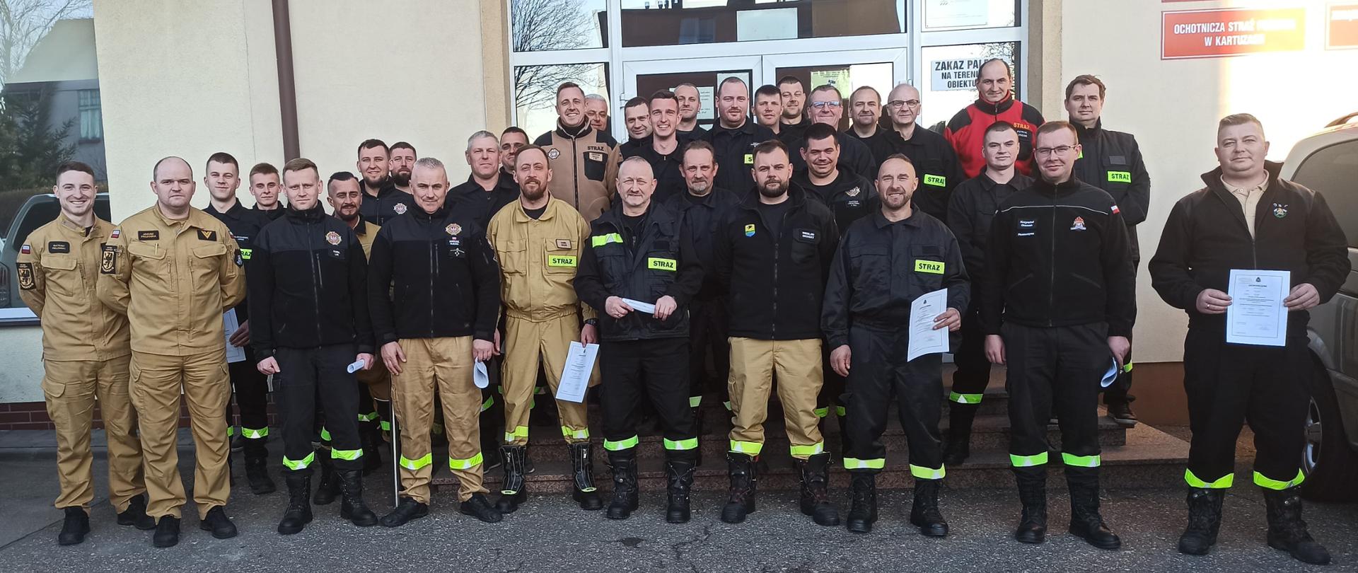 Zdjęcie grupowe strażaków po zakończonym szkoleniu dla kierowców-konserwatorów sprzętu ratowniczego OSP na tle budynku Komendy Powiatowej PSP w Kartuzach