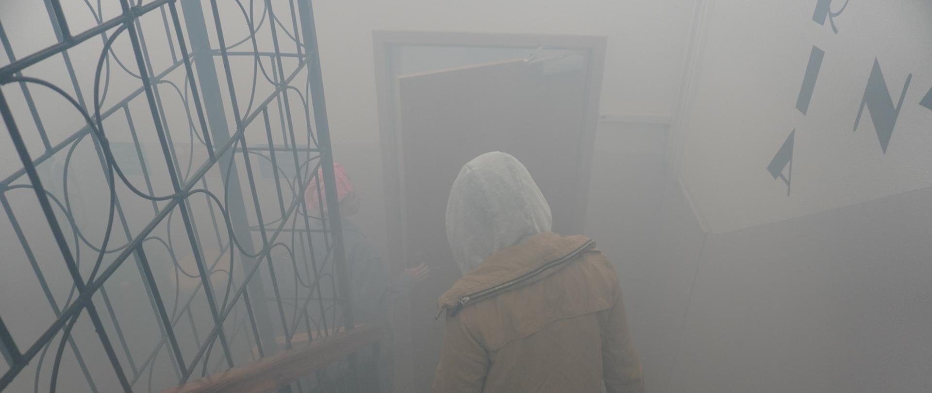 Wychowankowie przechodzą zadymioną klatką schodową.