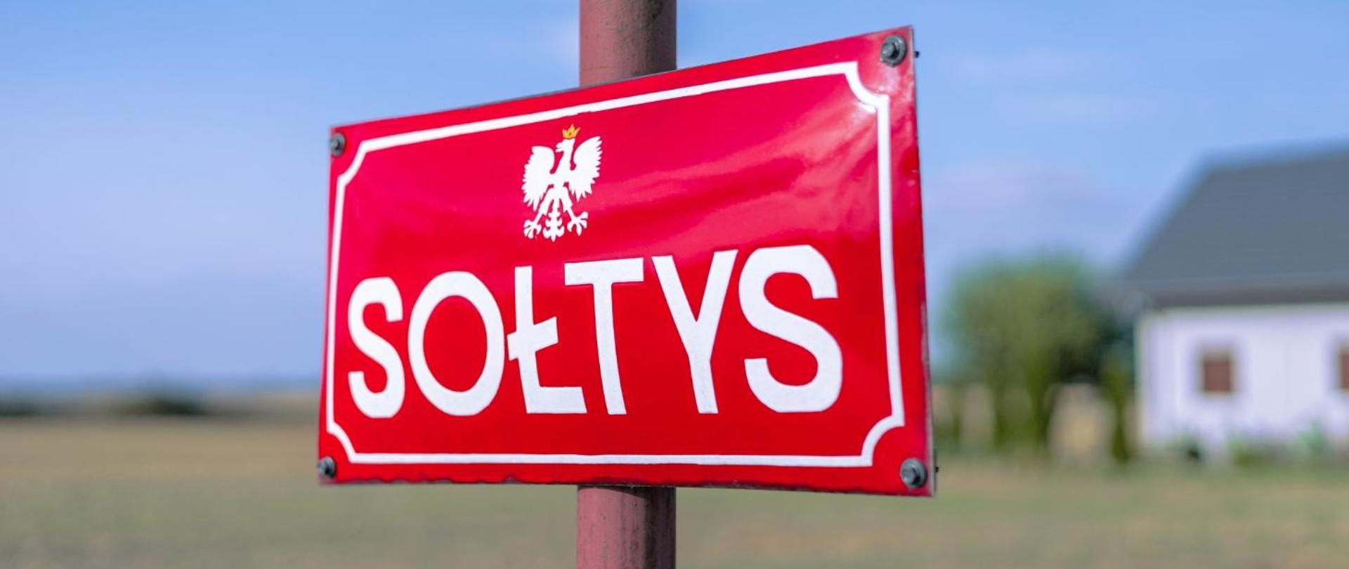 Czerwona tabliczka z białym napisem SOŁTYS