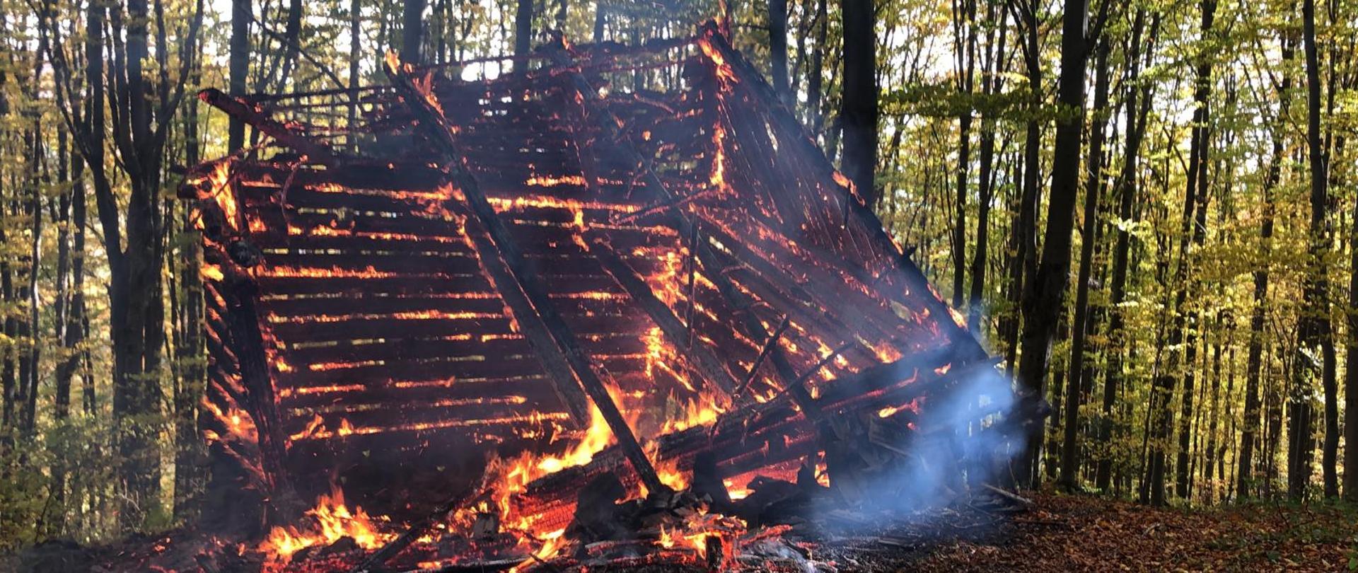 Płonący budynek w lesie