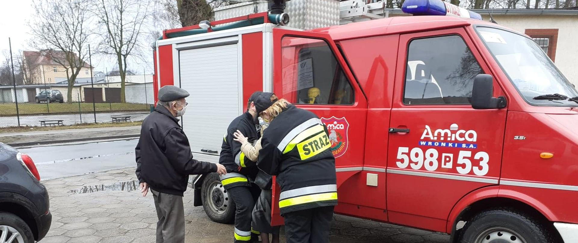 Strażacy pomagają starszej parze w transporcie do punktu szczepień