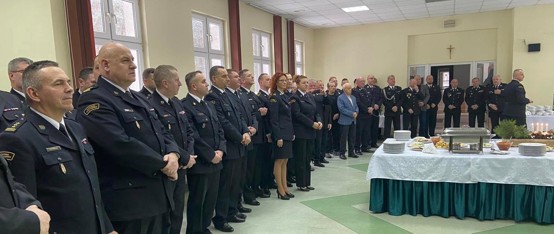 na zdjęciu funkcjonariusze psp wokol wigilijnego poczestunku. Przemawia zachodniopomorski komendant wojewodzki psp