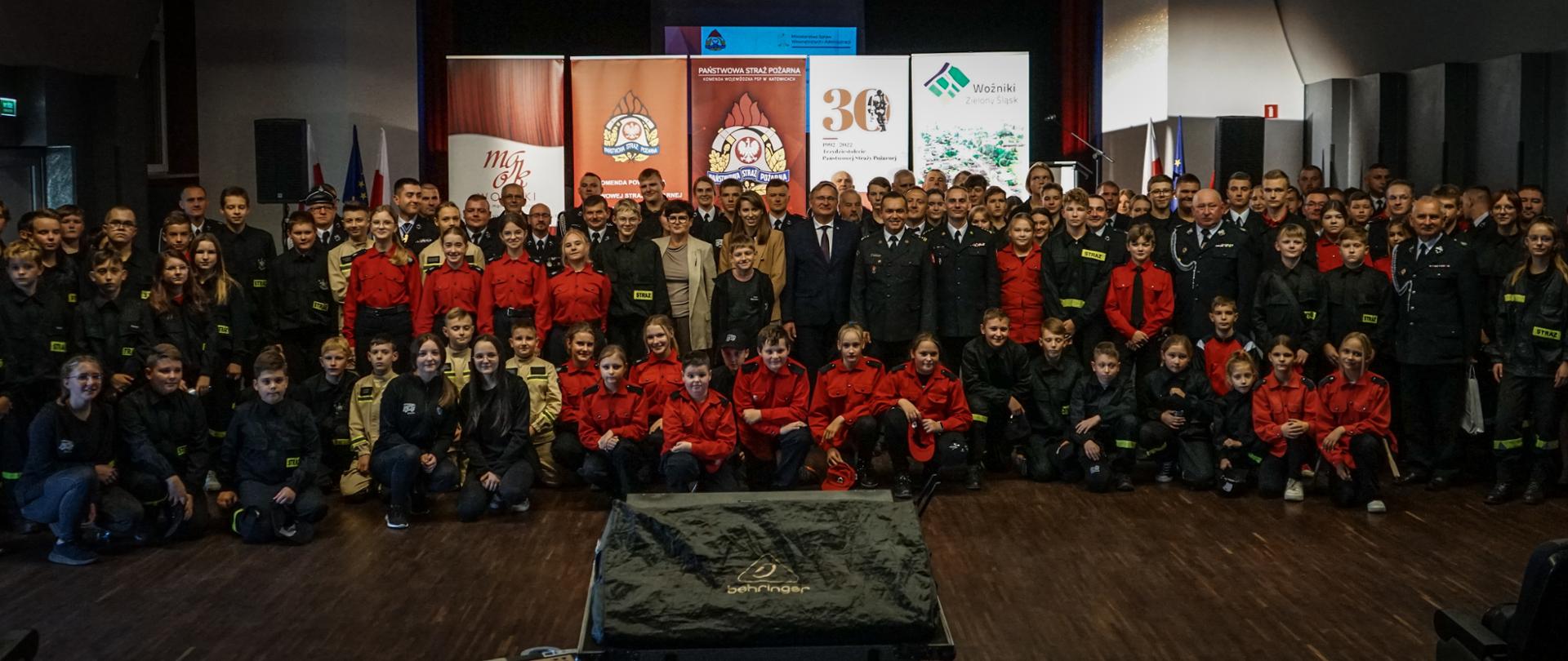Grupowe zdjęcie 36 Młodzieżowych Drużyn Pożarniczych z opiekunami. W centralnej części zaproszeni na uroczystość goście.