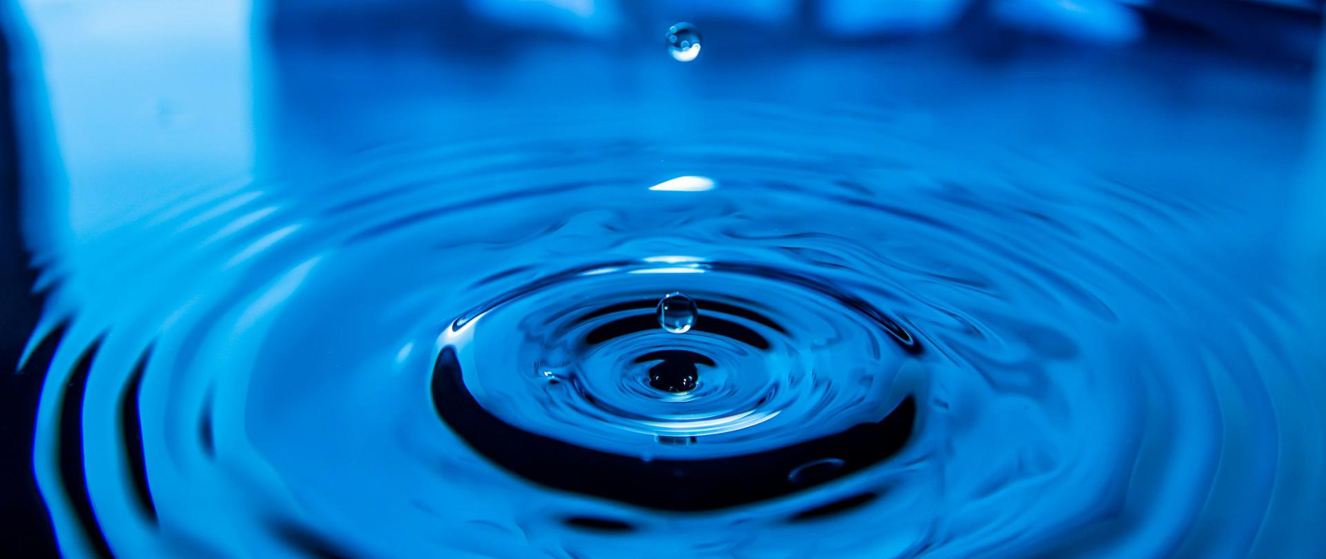 Grafika-przedstawiająca-kroplę-wody-nad-niebieską-wodą