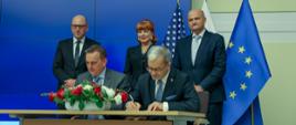 przy stoliku siedzą i podpisują list minister Jerzy Kwieciński i Fabrice Kermorgant z GE Renewable Energy, za nimi stoją wiceprezes ARP Dariusz Śliwowski, ambasador Georgette Mosbacher i Sławomir Żygowski z GE Power