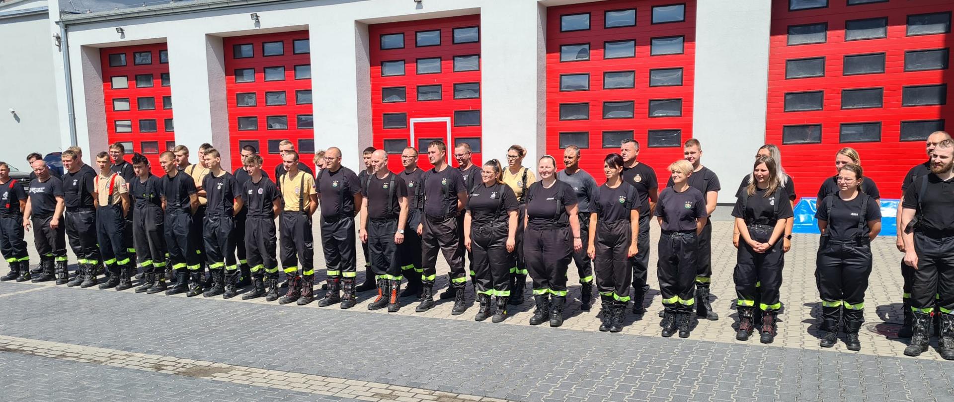 Strażacy na zdjęciu grupowym na tle komendy powiatowej