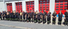 Strażacy na zdjęciu grupowym na tle komendy powiatowej