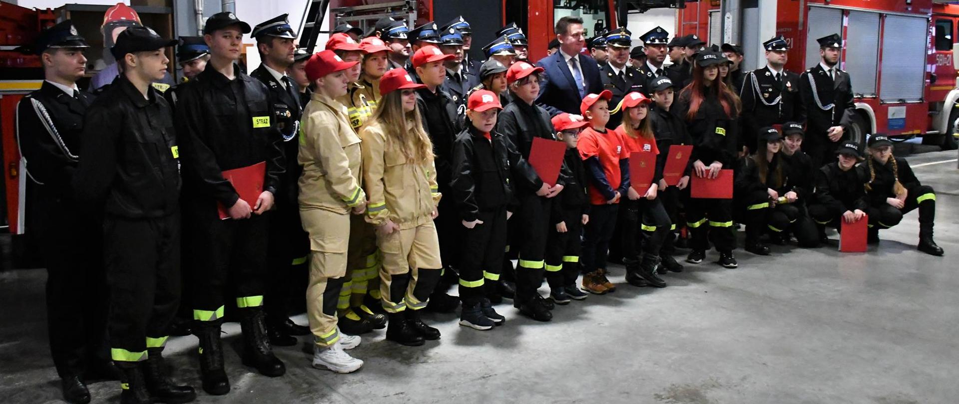 Na zdjęciu druhowie Młodzieżowych drużyn pożarniczych powiatu otwockiego w garażu komendy powiatowej PSP w Pruszkowie podczas uroczystego wręczenia promes pożarniczych.