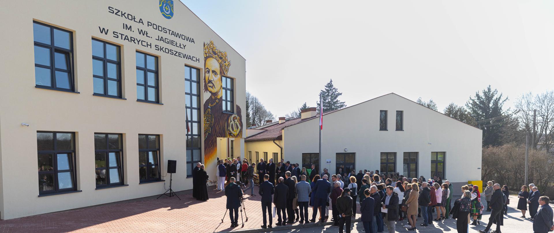 Uczestnicy uroczystego otwarcia nowej części szkoły, zgromadzeni przed budynkiem 