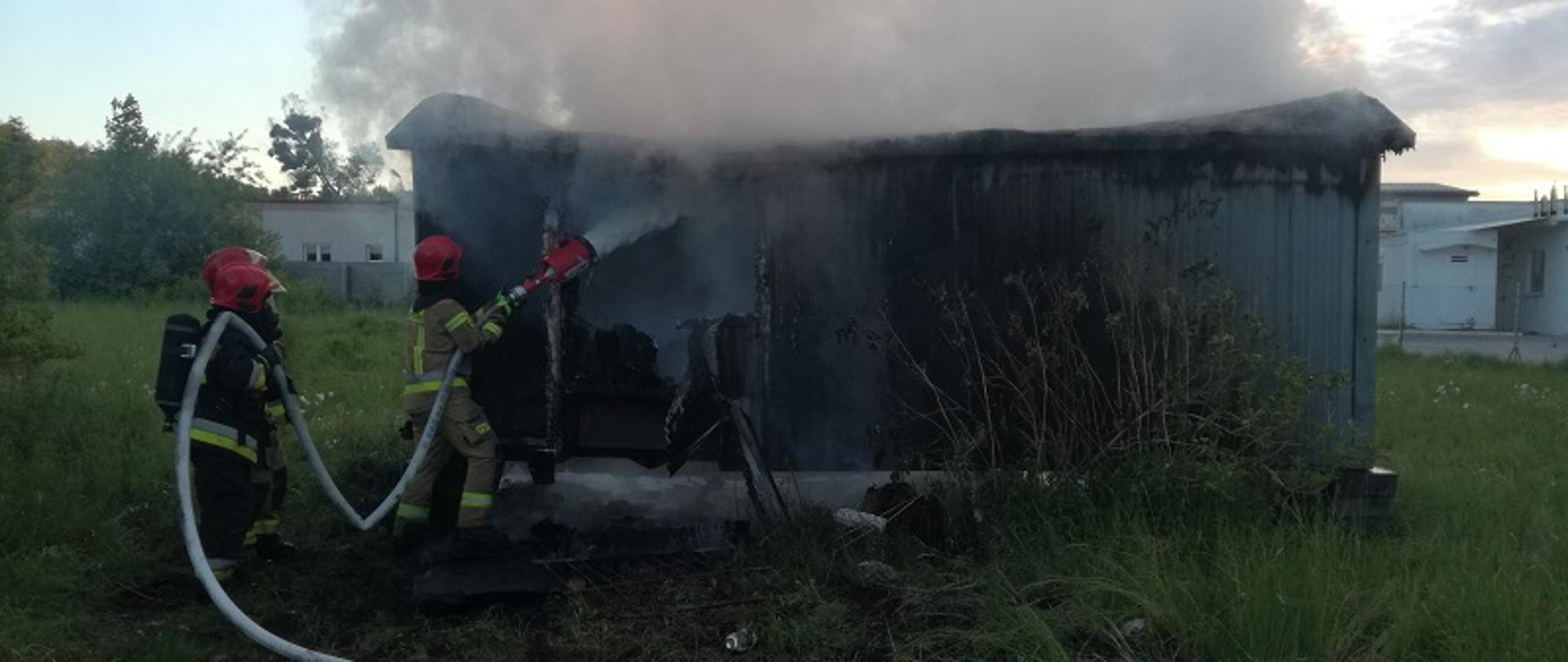 Zdjęcie przedstawia pożar wolnostojącego baraku na ul. Chocimskiej w Białogardzie. Strażacy w ubraniach specjalnych gaszą obiekt piana gaśniczą. Zastęp trzyma wąż pożarniczy zakończony wytwornicą pianową