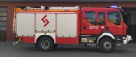 Czerwono biały duży samochód strażacki stoi bokiem/ na drzwiach biały numer 501 E 21
