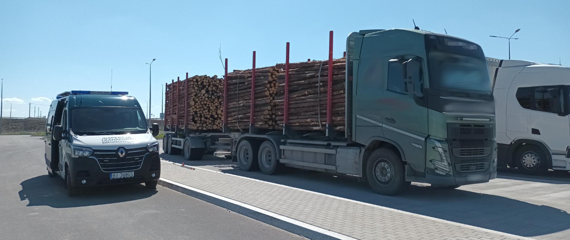 Ciężarówka załadowana kłodami drewna stoi obok radiowozu ITD