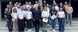 Pamiątkowe zdjęcie grupowe uczestników szkolenia inspektorów ochrony przeciwpożarowej (26 osób) w towarzystwie Zastępcy Komendanta Centralnej Szkoły PSP oraz funkcjonariusza CS PSP