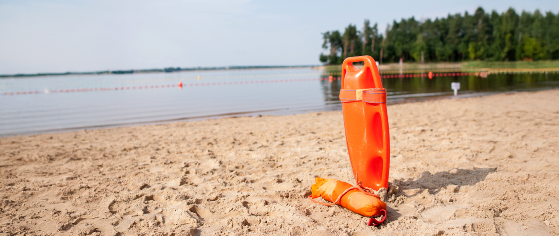 Deska ratunkowa i boja na piasku, na tle jeziora