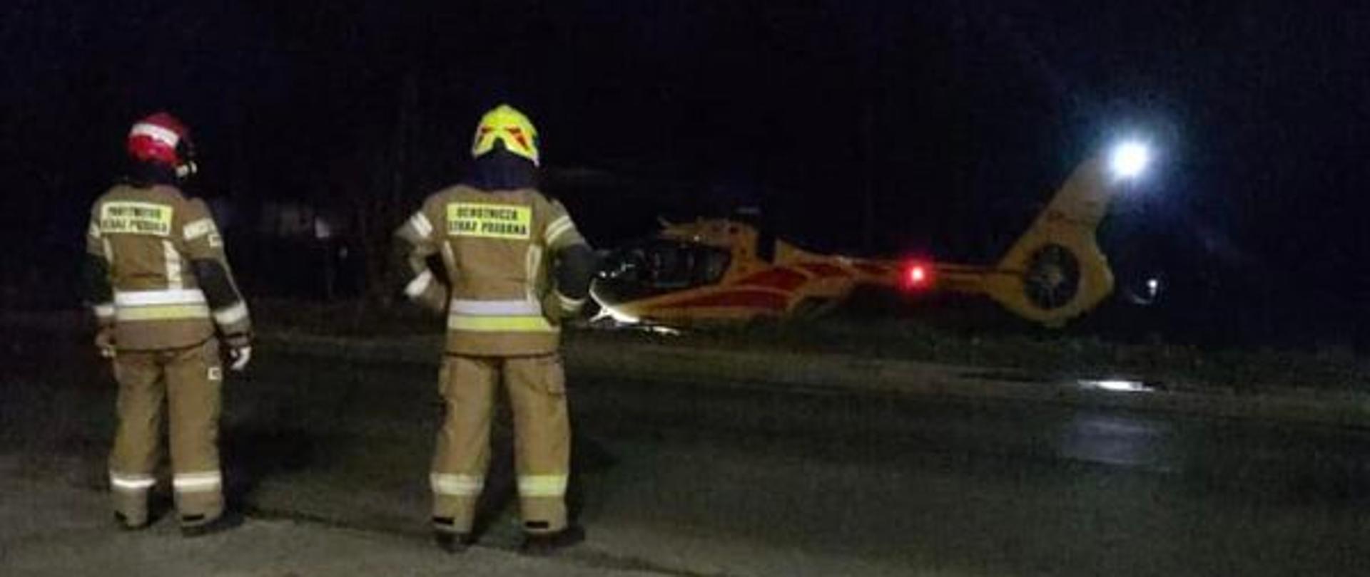 Na zdjęciu znajdują się strażacy w tle widać śmigłowiec LPR, sytuacja ma miejsce po zmroku