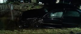 Na zdjęciu po za drogą krajową numer dwanaście doszło do kolizji drogowej dwóch samochodów osobowych marki Audi. Jeden z samochodów wypadając z drogi uszkodził betonowe ogrodzenie przy posesji. 