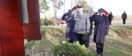 Na zdjęciu widoczni funkcjonariusze komendy powiatowej państwowej straży pożarnej w Sochaczewie oraz komendy powiatowej policji, którzy po złożeniu wieńca pod krzyżem oddają honor salutując do czapek.