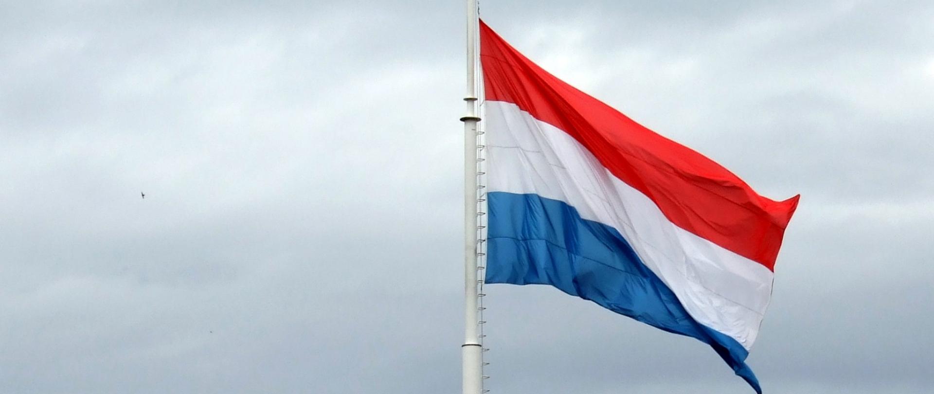 Zapowiedź udziału wiceministra Grzegorza Piechowiaka na posiedzenie Rady ds. Zagranicznych w Luksemburgu. Na zdjęciu widać flagę Luksemburga.