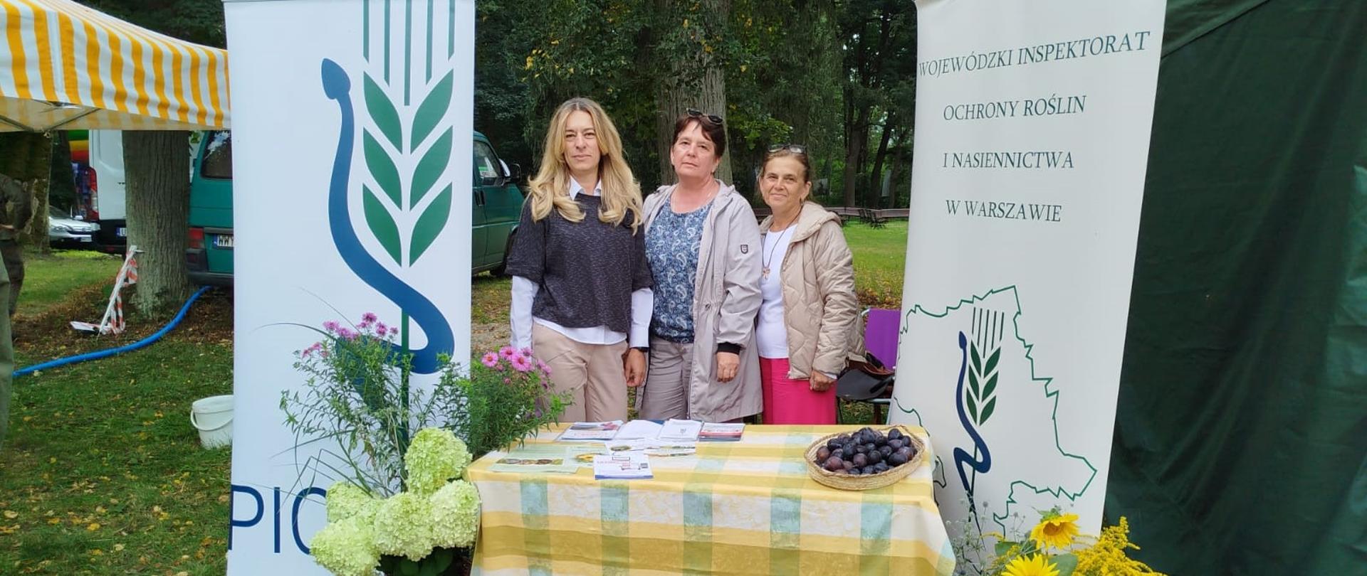 Na zdjęciu grupa 3 kobiet przy stole ozdobionym rożnymi roślinami. Obok banerów PIORiN