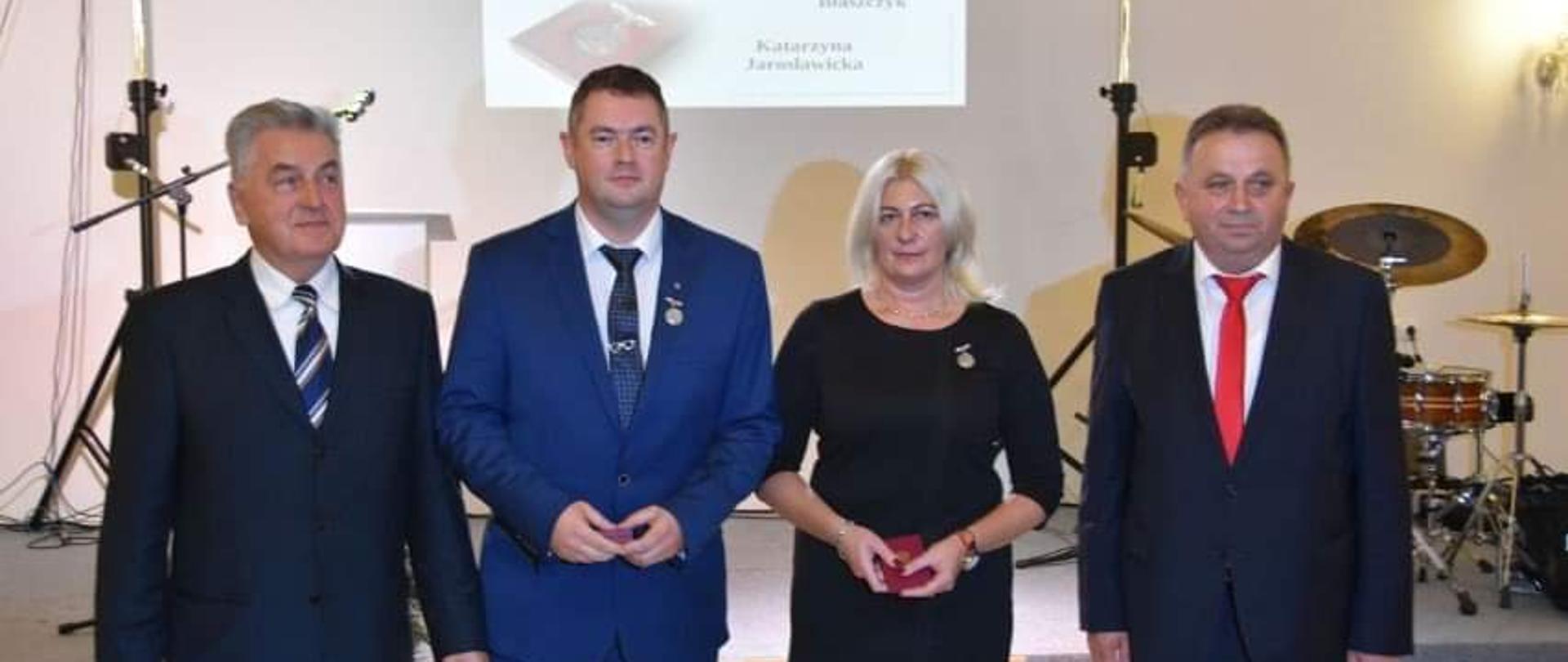 Wojewoda z odznaczonymi pozuje do wspólnego zdjęcia na tle sceny,