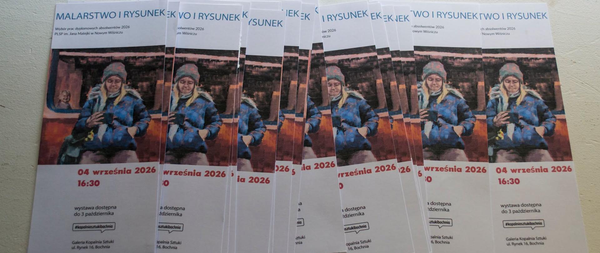 Na blacie ułożone w harmonijkę ulotki z widocznymi fragmentami obrazu i tekstu, reklamujące wystawę
