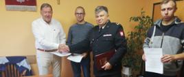 Na zdjęciu komendant powiatowy PSP w Grajewie w mundurze wyjściowym podający rękę wójtowi gminy Wąsosz oraz druhowie OSP w cywilnych ubraniach.