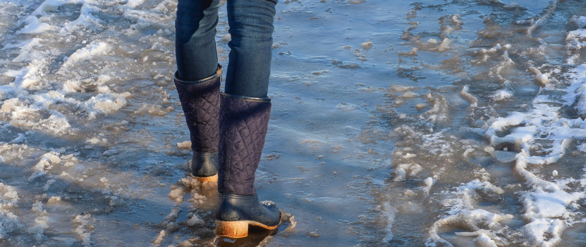 człowiek w kaloszach na oblodzonym chodniku