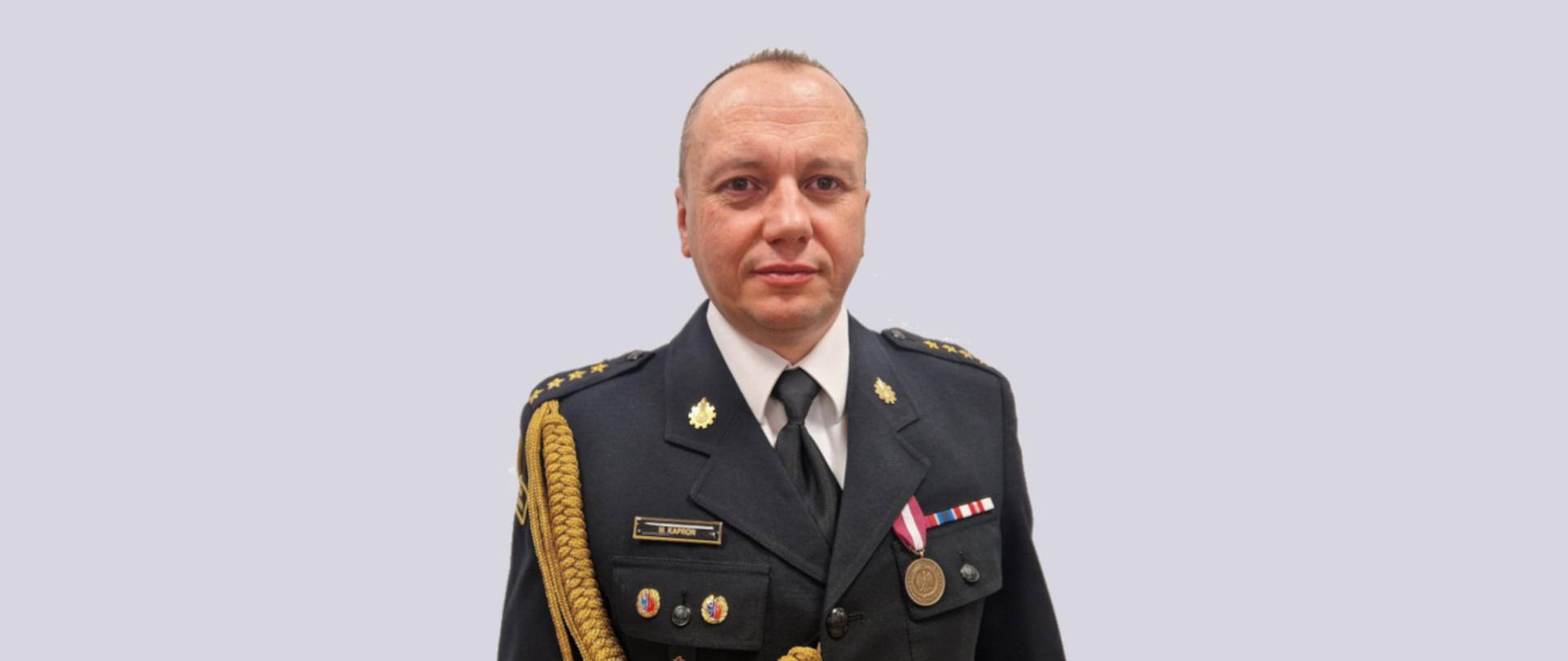 Zdjęcie portretowe p.o. zastępca komendanta st. kpt. Marcin Kaproń na jasnym tle w mundurze galowym