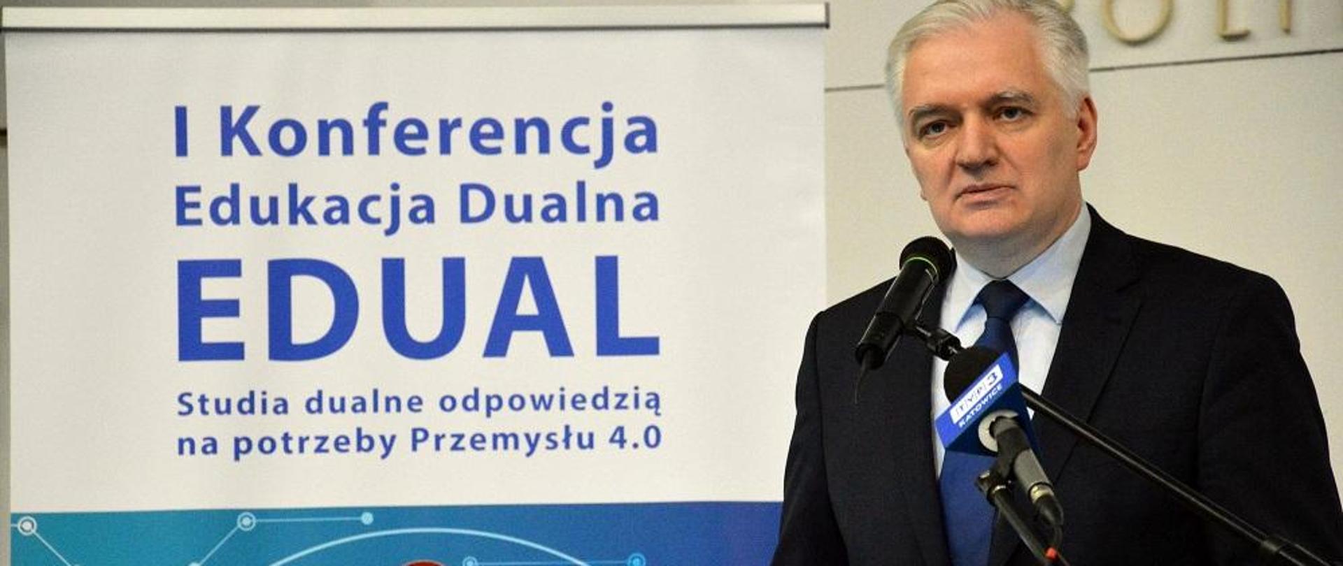 Minister Gowin przemawia do mikrofonu, w tle plakat I Konferencja EDUAL