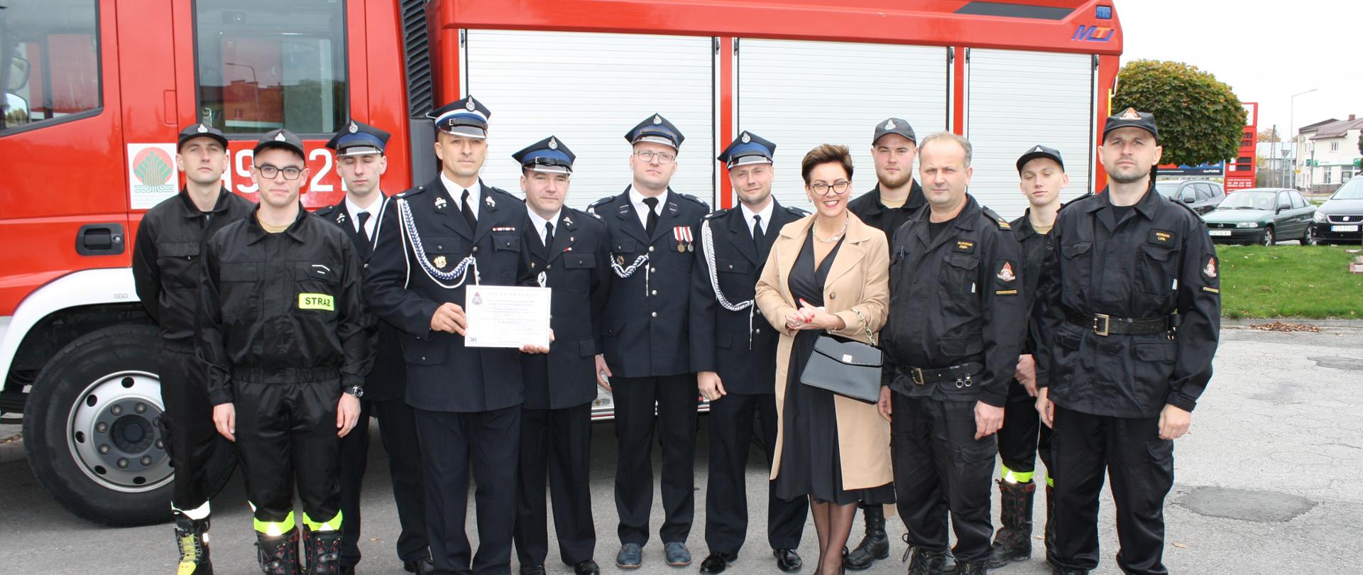 Strażacy psp i osp na czele z komendantem powiatowym oraz wójtem gminy brody przed przekazywanym pojazdem