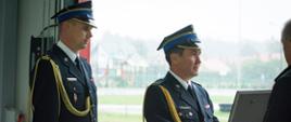 Fotografia przedstawia w umundurowaniach galowych: zastępcę podkarpackiego komendanta wojewódzkiego Państwowej Straży Pożarnej bryg. Andrzeja Marczenię i stojącego obok komendanta powiatowego Państwowej Straży Pożarnej w Mielcu mł.bryg. Łukasza Kapinosa. Zastępca podkarpackiego komendanta wojewódzkiego w rękach trzyma decyzję oprawioną w ozdobną ramkę o włączeniu jednostki do krajowego systemu ratowniczo gaśniczego