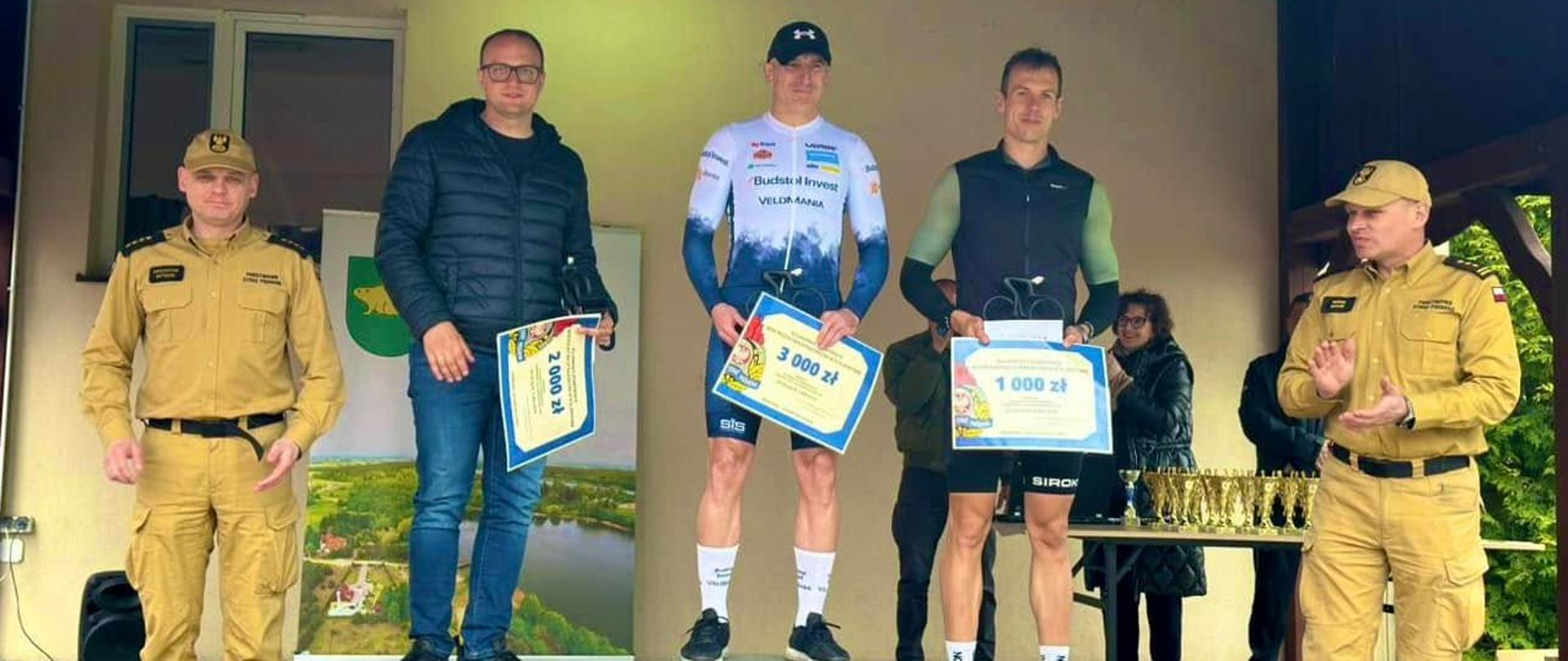 Zwycięzcy Kujawsko-Pomorskich Mistrzostw Strażaków w Kolarstwie na podium. 1 miejsce Leszek Kusiowski, 2 miejsce Mateusz Kościński, 3 miejsce Jakub Piechowiak.
