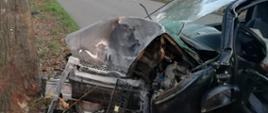 Samochód osobowy uderzył w drzewo, .ma rozbity przód, wybitą szybę przednią i otwarte drzwi od strony kierowcy. 
