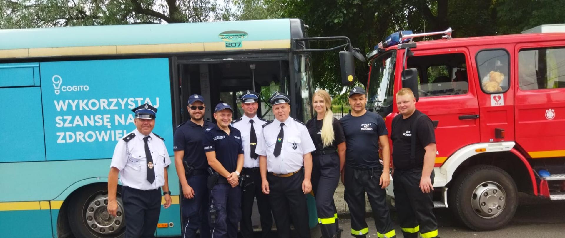 Zdjęcie przedstawia strażaków na tle autobusu "punkt szczepień"