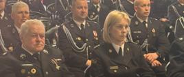 Na zdjęciu widać zgromadzonych gości (strażaków) ubranych w mundury służbowe, którzy siedzą na krzesłach. Odprawa odbywa się w garażu siedziby KP PSP Węgrów. 