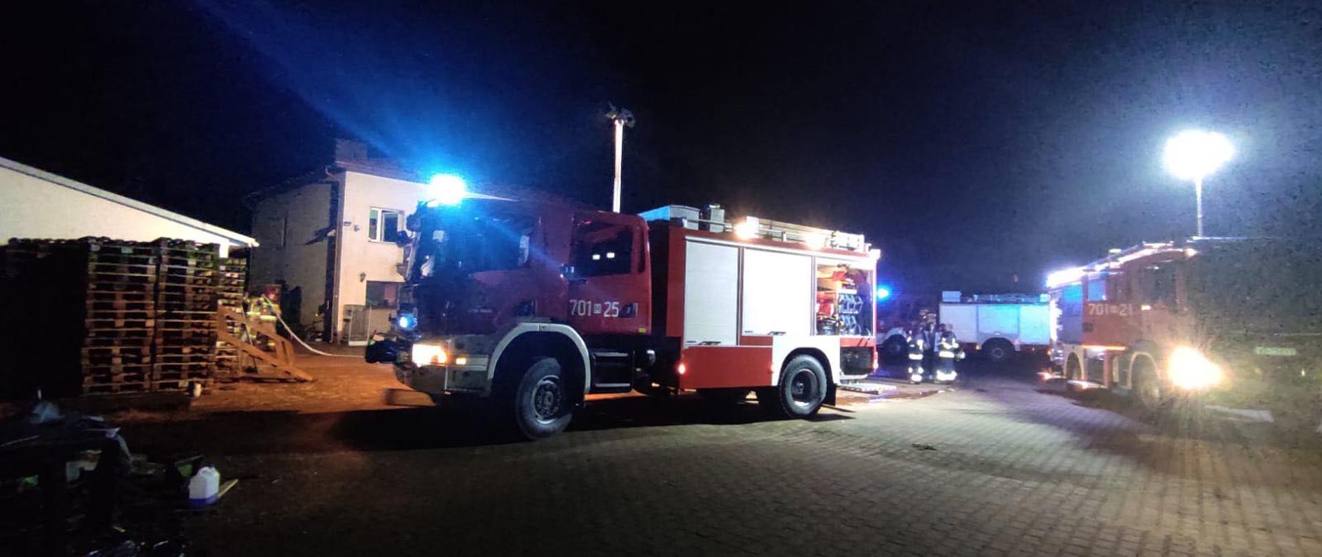 Zdjęcie przedstawia ciężki samochód scania, jest ciemno, w tle widać strażaków oraz inny samochód strażacki