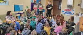Wizyta w ramach akcji „Odwiedź strażnicę i salę edukacyjną typu Ognik” w KP PSP w Soko-łowie Podlaskim 21.03.2023 r. na zdjęciu strażacy omawiają dzieciom: :codzienną służbę strażaka, wyposażenie pojazdów pożarniczych, procedury przyjmowania zgłoszeń o zdarzeniu, zasady alarmowania i postępowania na wypadek pożaru i innego zagrożenia