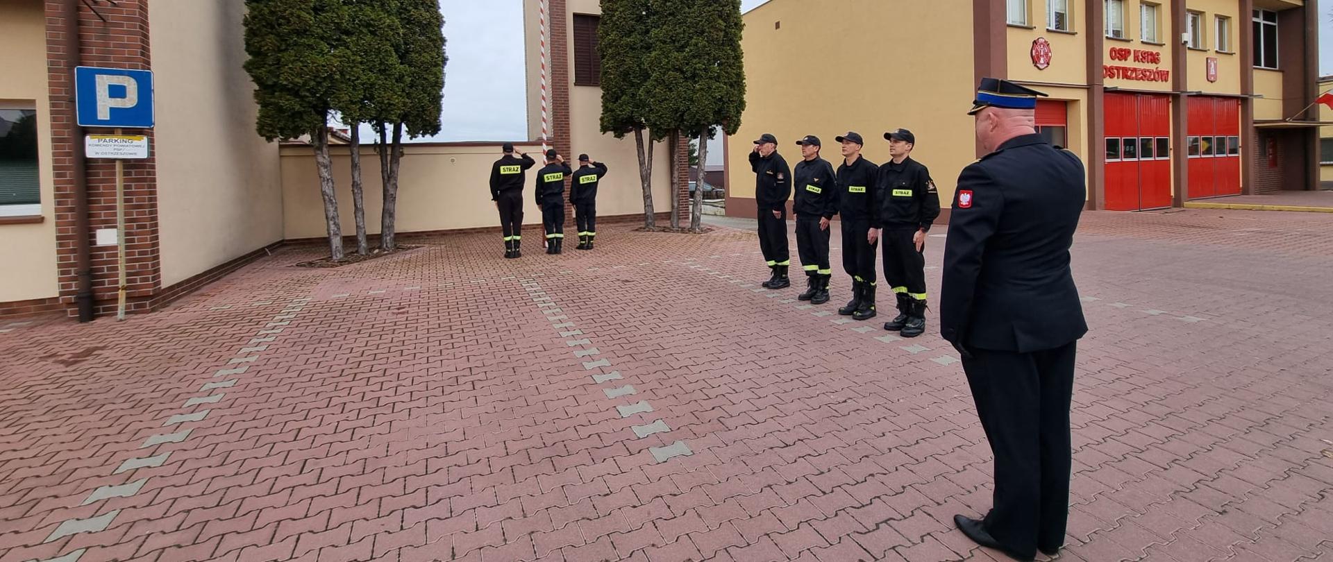 Strażacy stoją na placu manewrowym podczas obchodów święta niepodległości