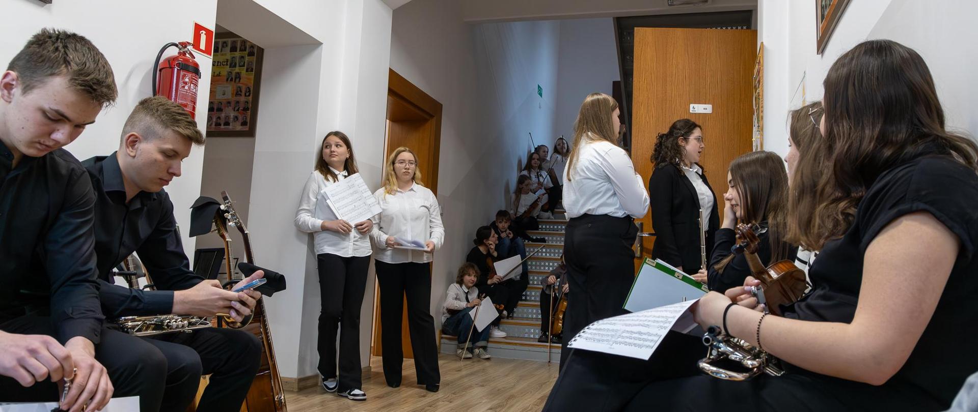 XVIII Szkolny Konkurs Zespołów Kameralnych. Uczestnicy konkursu na korytarzu przed aulą oczekują na swoje prezentacje.
