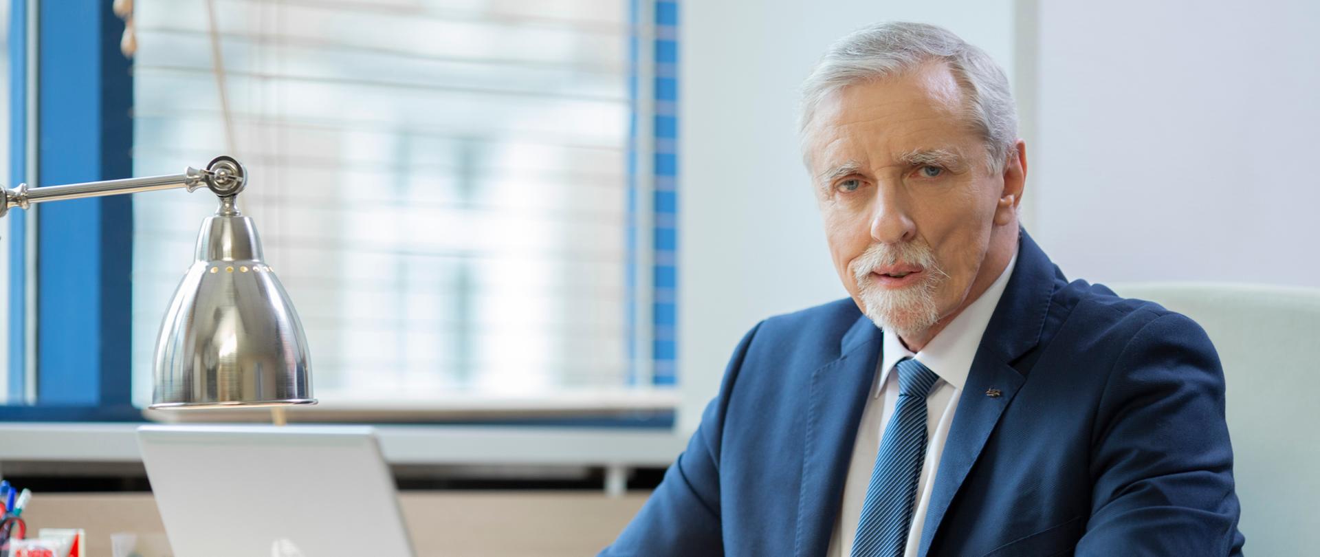 Elegancko ubrany mężczyzna siedzący za biurkiem