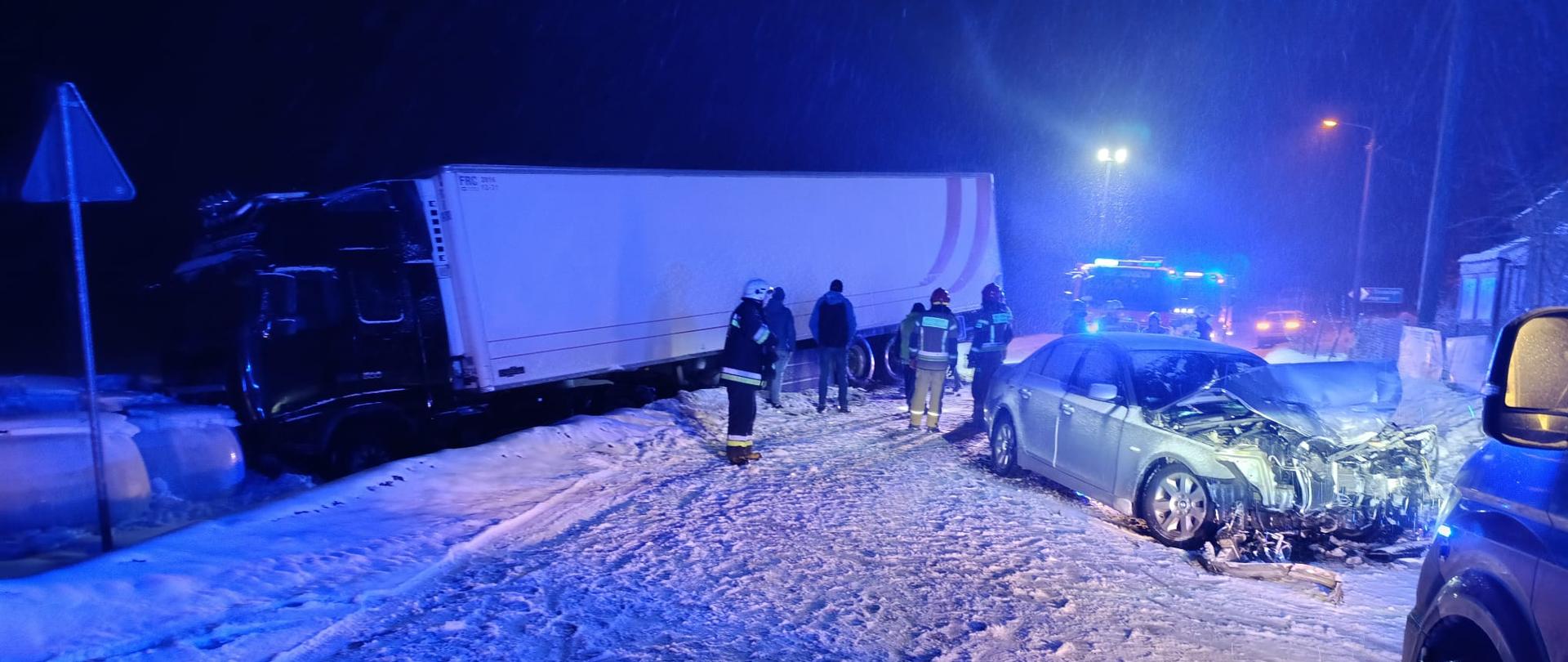 Zderzenie dwóch pojazdów, pracujące służby mundurowe na drodze.