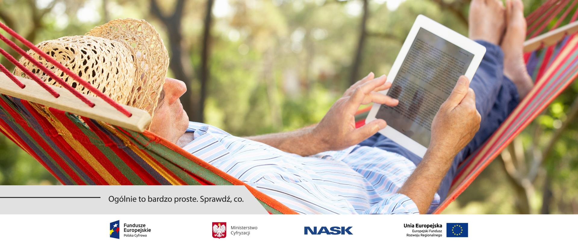 Mężczyzna w słomianym kapeluszu leżący w kolorowym hamaku zawieszonym wśród drzew. Trzyma w rękach biały tablet, na którym wyświetla się jakiś dokument. Pod obrazkiem napis: Ogólnie to bardzo proste. Sprawdź, co.
