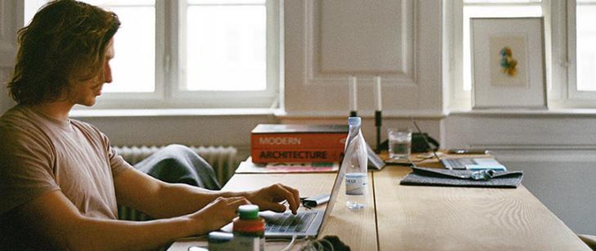 Mężczyzna siedzący przy stole z laptopem. 