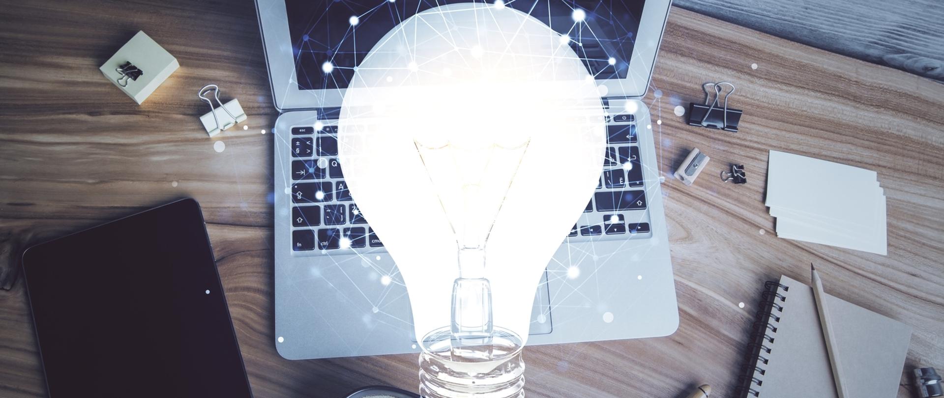 Grafika przedstawia laptopa i symbol żarówki